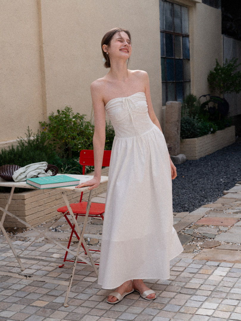 Woman wearing a white strapless maxi dress and sandals outdoors