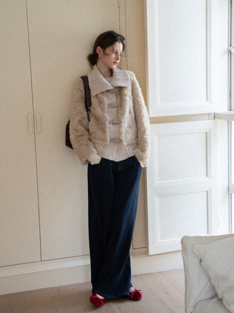 Woman wearing a cozy beige fur jacket with a cream knit sweater, wide-leg dark pants, and red flats