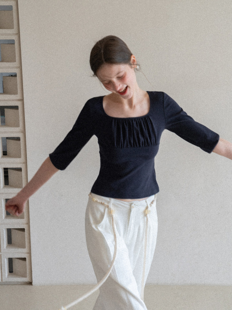 Model wearing a navy square-neck top with three-quarter sleeves and white pants