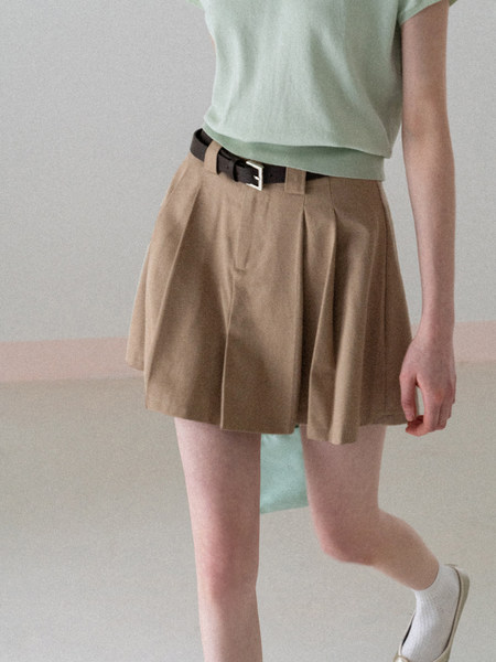 Model wearing khaki pleated shorts with a belt