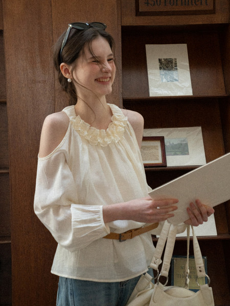 White off-shoulder ruffled blouse worn by a woman with jeans