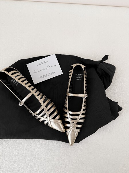 Pair of silver strappy flat sandals on black fabric