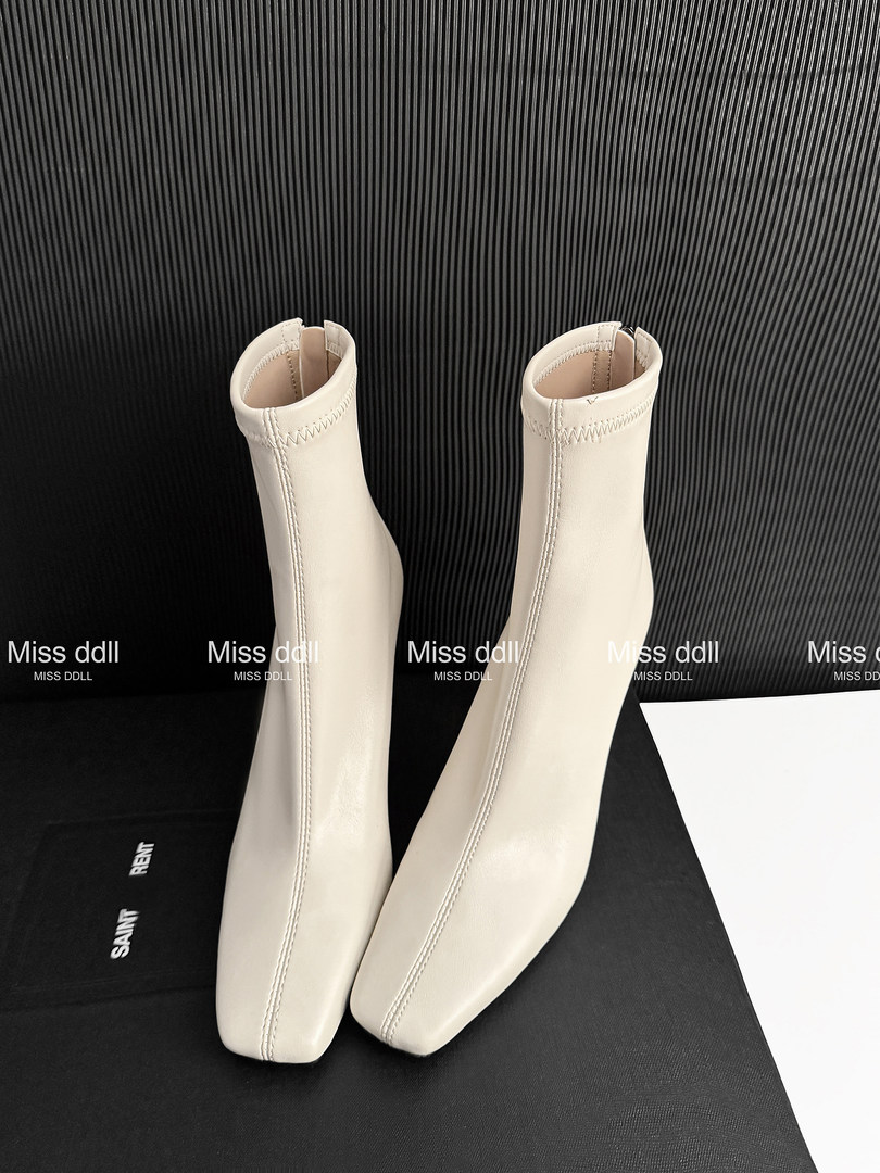 Pair of cream ankle boots on a dark display background