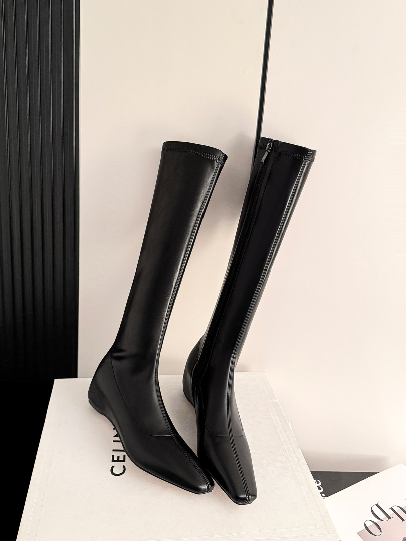 Black knee-high heeled boots displayed on a box