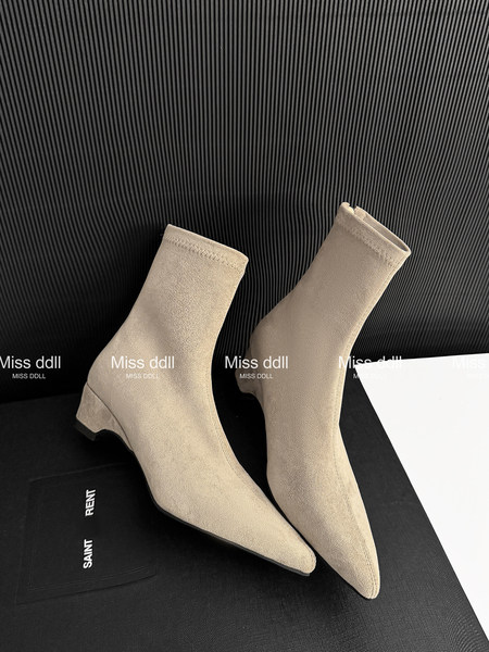 Beige pointed-toe ankle boots displayed on a black surface