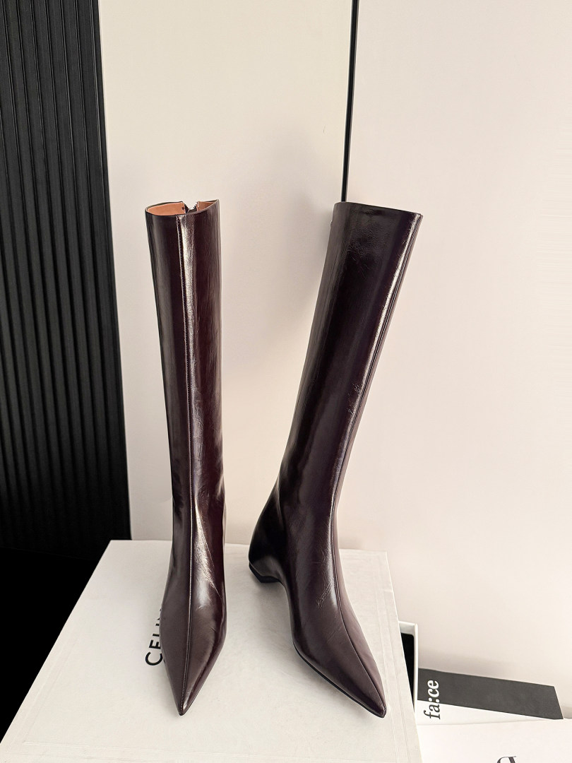 Pair of glossy dark brown knee-high pointed-toe boots on display