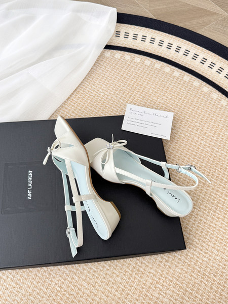Pair of cream strappy heeled sandals with bows on a branded box