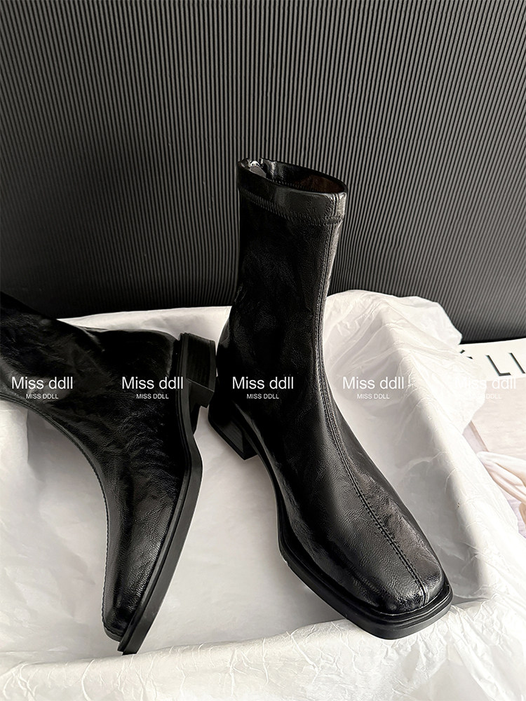 Black ankle boots displayed on a bed