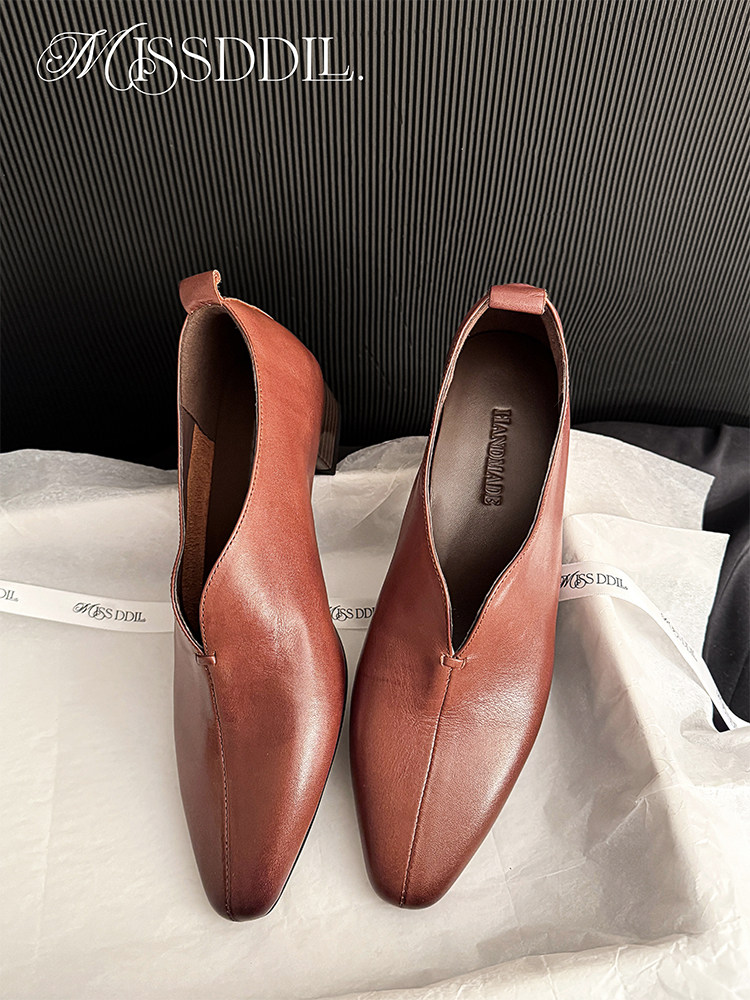 Brown leather heeled loafers displayed on packaging paper