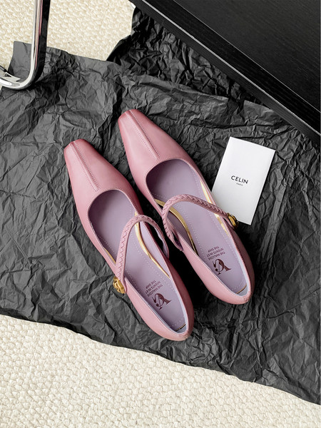 Pair of pink pointed-toe flats with ankle straps on black wrapping paper