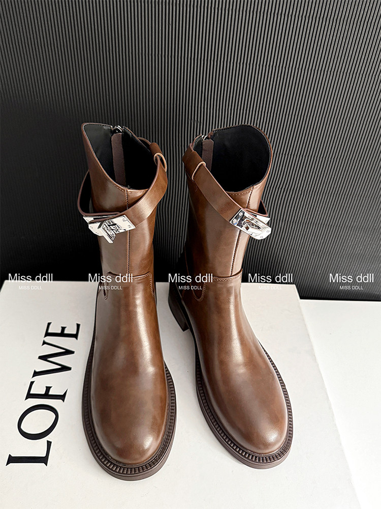 Brown leather ankle boots with side buckles on a display box