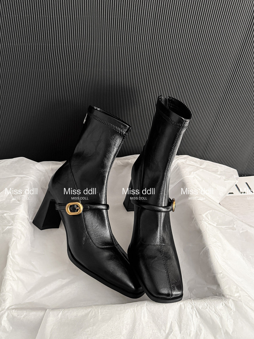 Black heeled ankle boots with gold buckle detail on display
