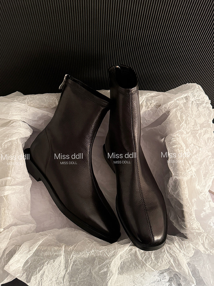 Pair of black ankle boots displayed on tissue paper