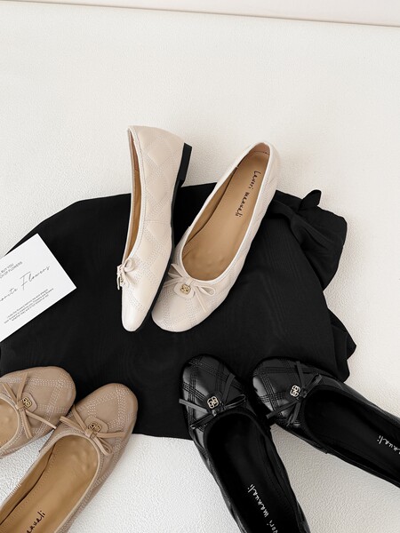 Collection of quilted pointed-toe ballet flats in black, beige, and cream arranged on a fabric backdrop