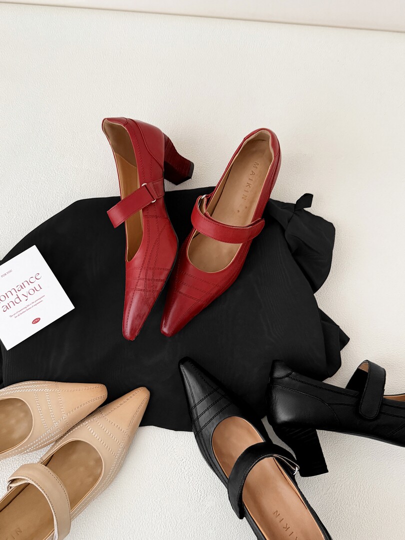 Flat lay of pointed-toe Mary Jane heels in red, black, and beige.
