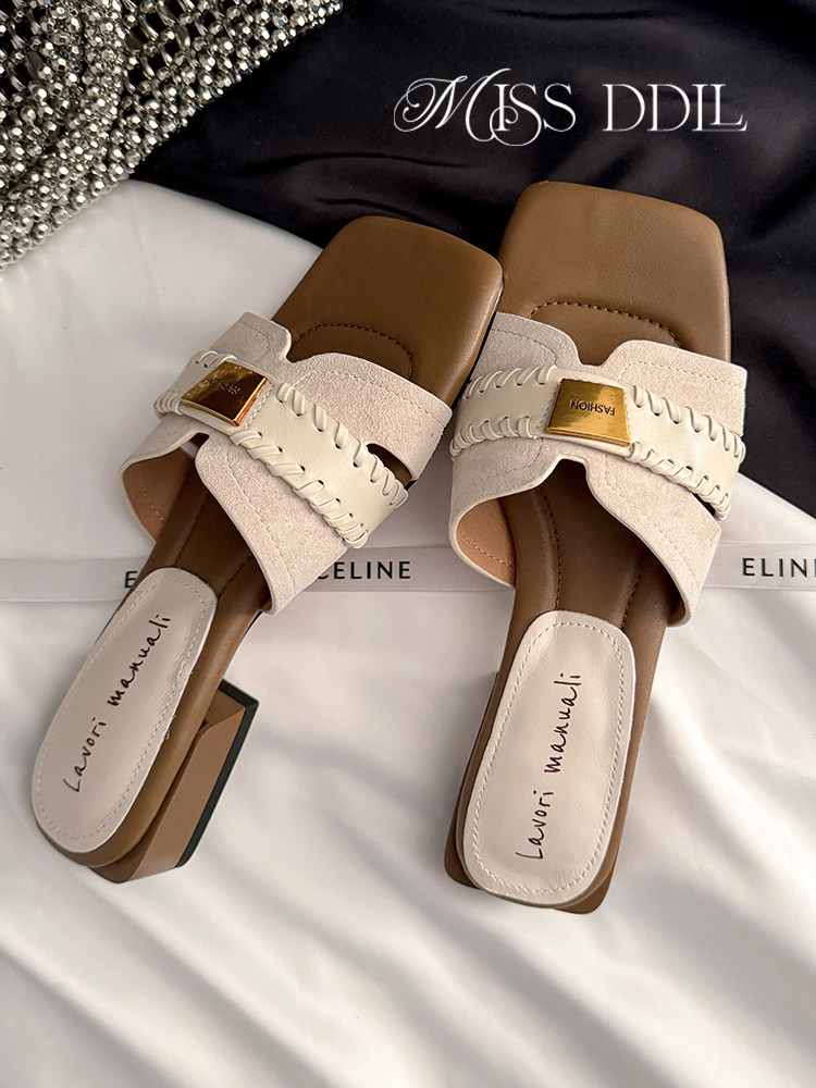 Pair of beige heeled slide sandals on a display surface