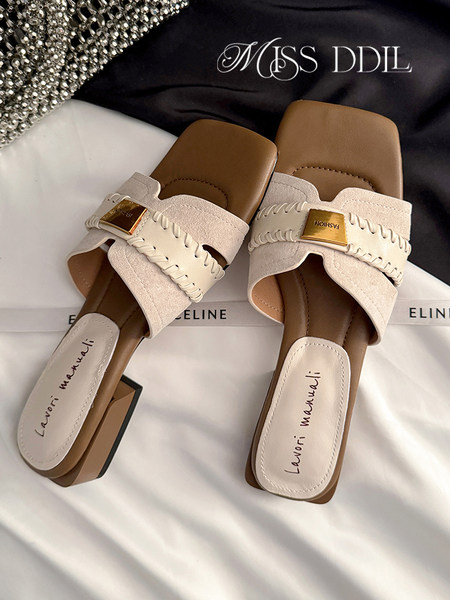 Pair of beige heeled slide sandals on a display surface