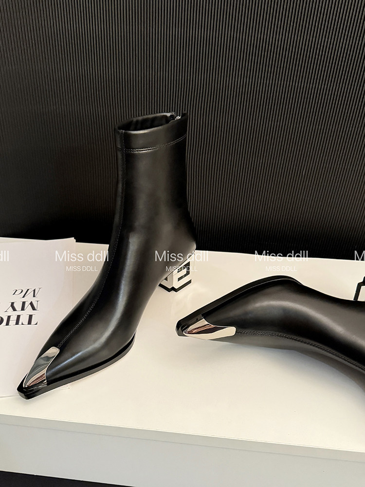 Black pointed-toe ankle boots with metallic toe caps displayed on a box