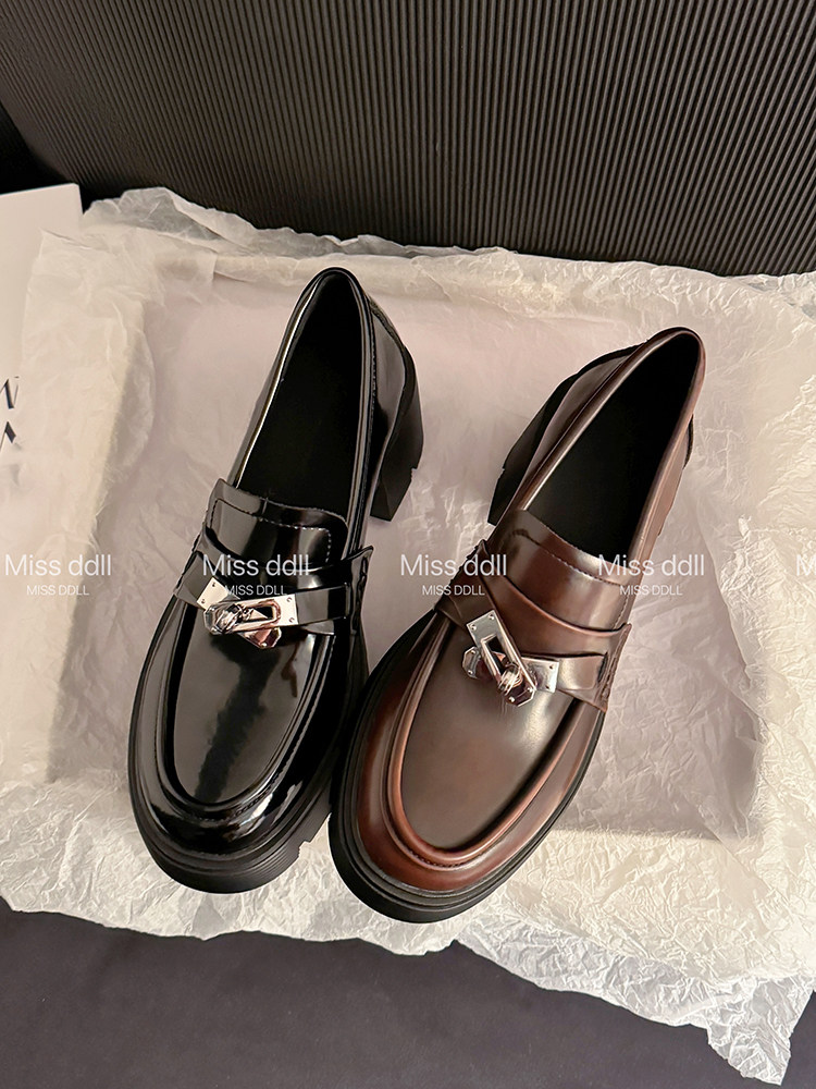 Pair of glossy buckle loafers in black and brown on tissue paper