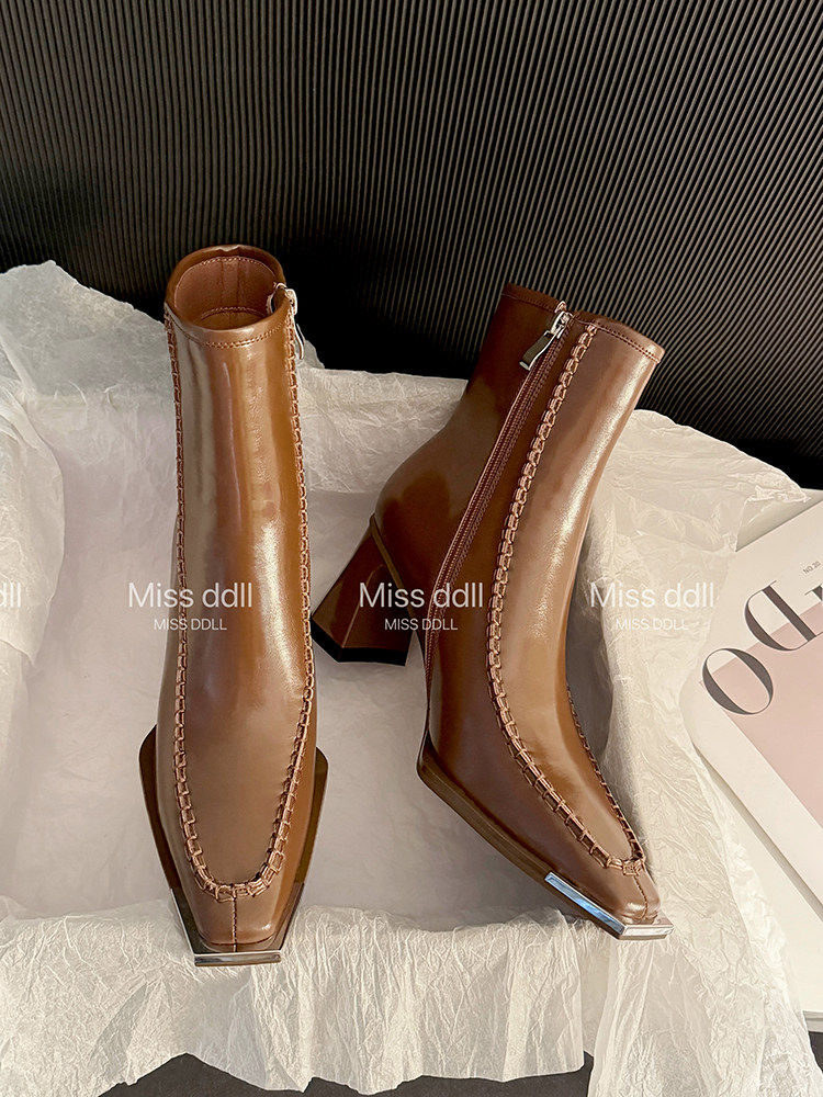 Pair of brown heeled ankle boots displayed on tissue paper