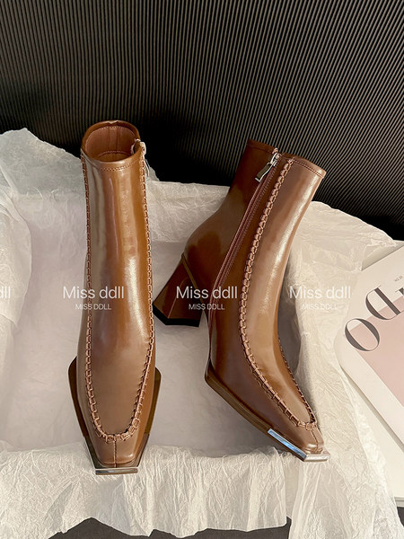 Pair of brown heeled ankle boots displayed on tissue paper
