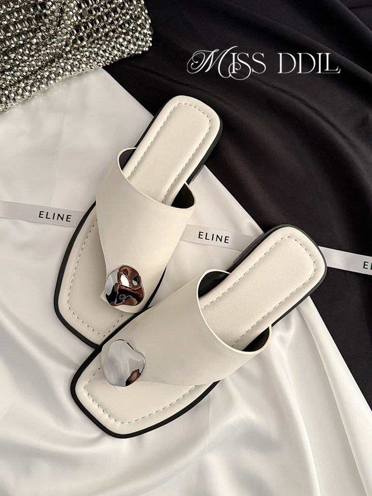 Pair of cream square-toe slide sandals with metallic accents