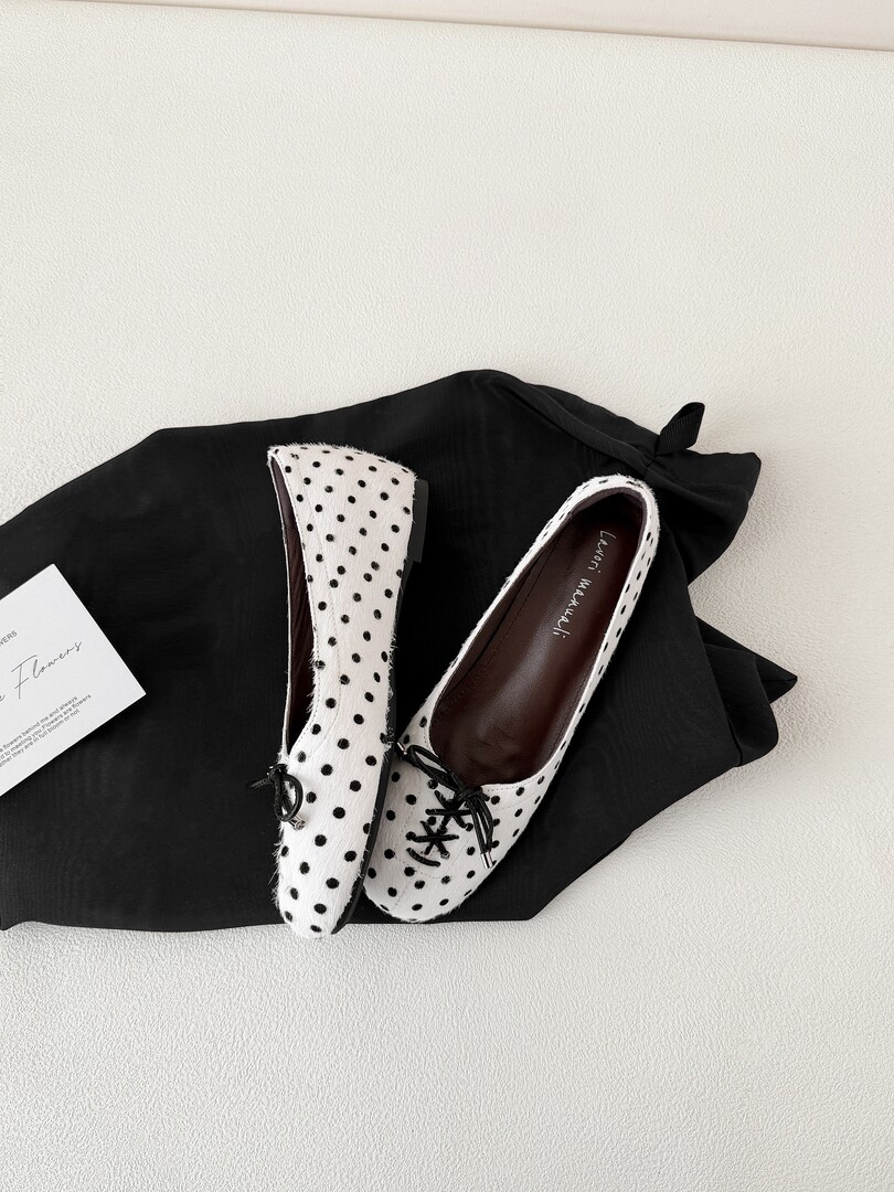 White polka dot flats shoes displayed on black fabric