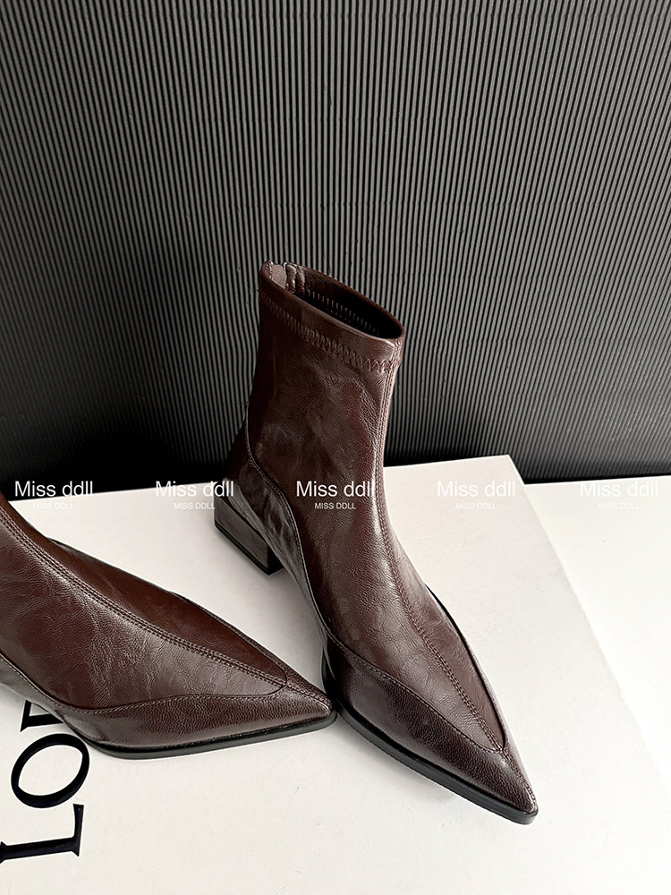 Brown pointed-toe heeled ankle boots on a white surface