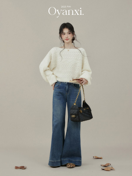 Model wearing a white knit sweater with flared blue jeans and a black quilted handbag