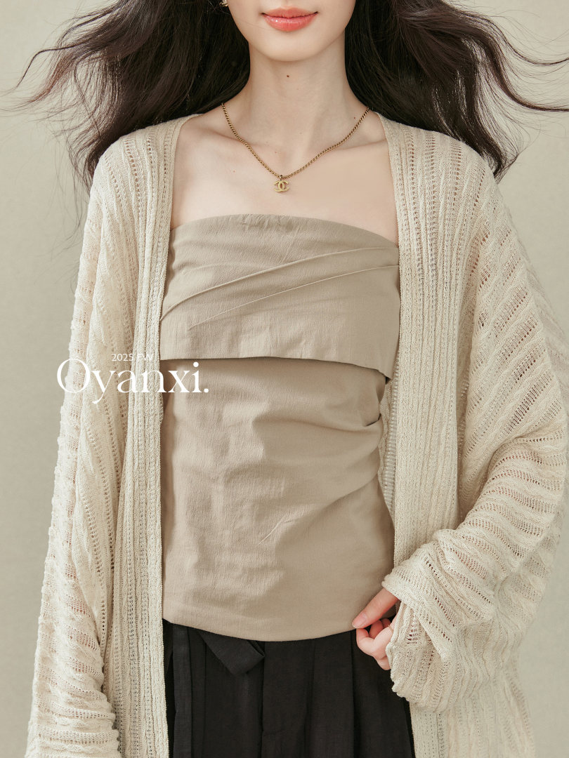 Model wearing a beige strapless top with a cream open-knit cardigan
