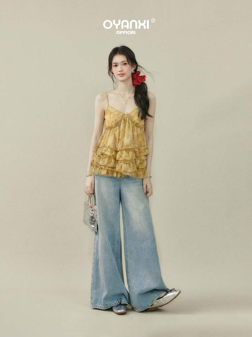 Model wearing a yellow ruffled camisole top with wide-leg light blue jeans
