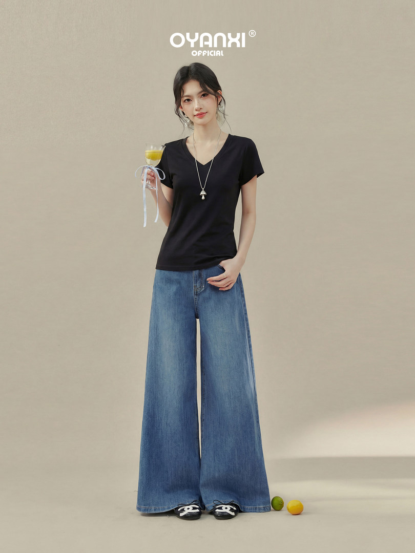 Model wearing a black V-neck T-shirt and wide-leg blue jeans