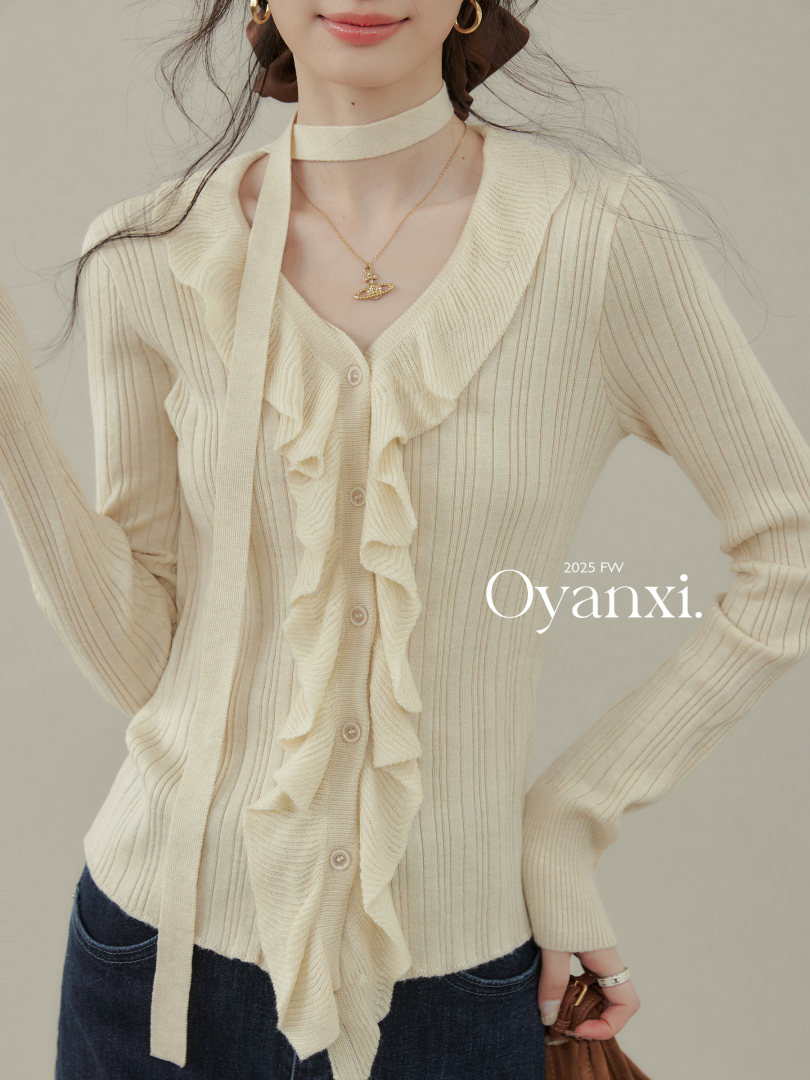 Model wearing a cream ruffled knit cardigan with ribbon tie detail