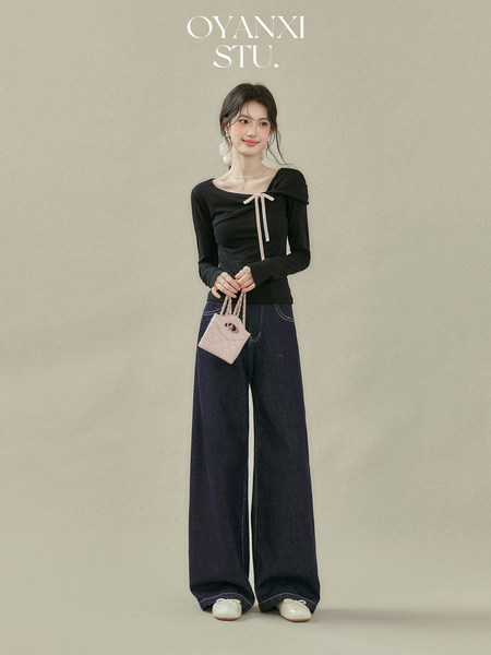 Model wearing a black long-sleeve top with wide-leg dark jeans and a small quilted handbag
