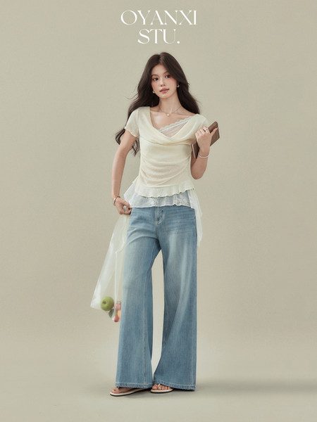 Fashion model wearing a cream layered top with wide-leg blue jeans