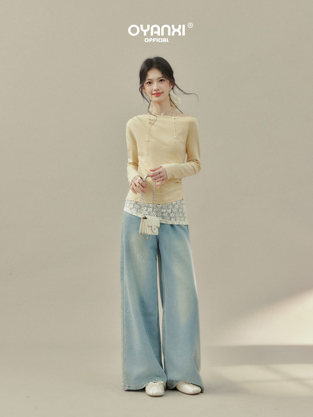 Model wearing a pale yellow off-shoulder top and light blue wide-leg embroidered jeans