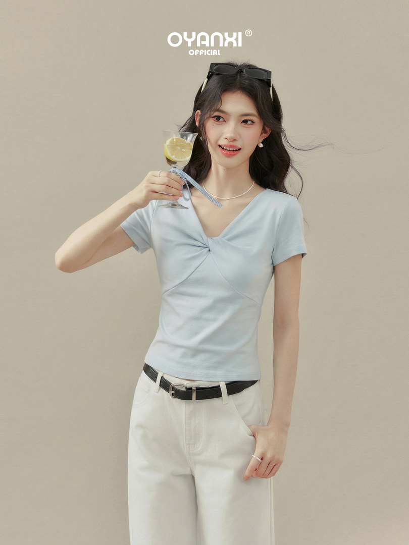 Model wearing a light blue twisted-front short sleeve top with white pants