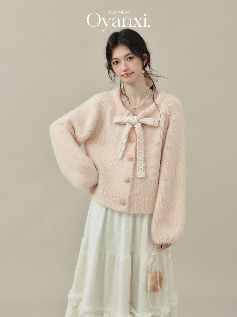 Model wearing a pastel pink fuzzy cardigan with a white skirt