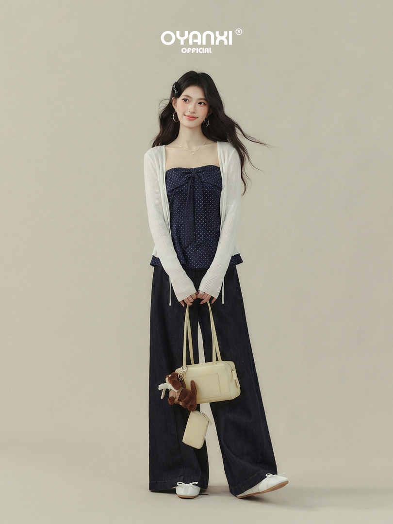 Model wearing a navy strapless top, white cardigan, wide-leg pants, and white flats