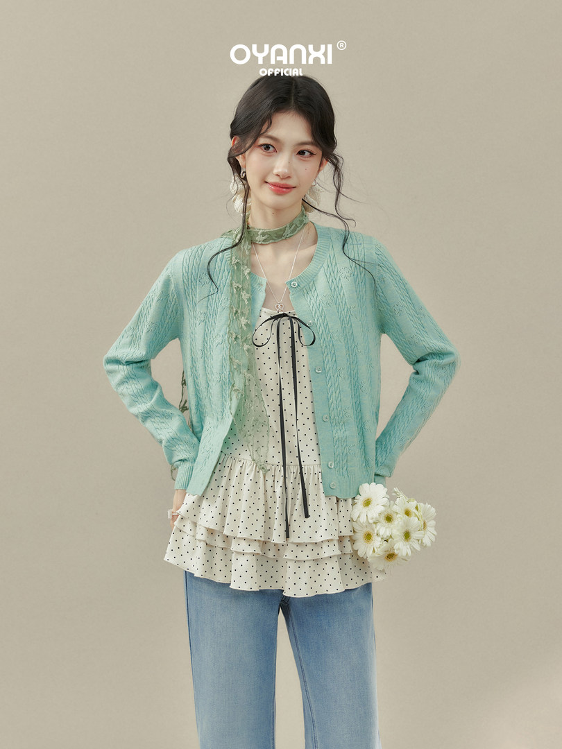 Model wearing a mint knit cardigan over a polka dot layered top with jeans