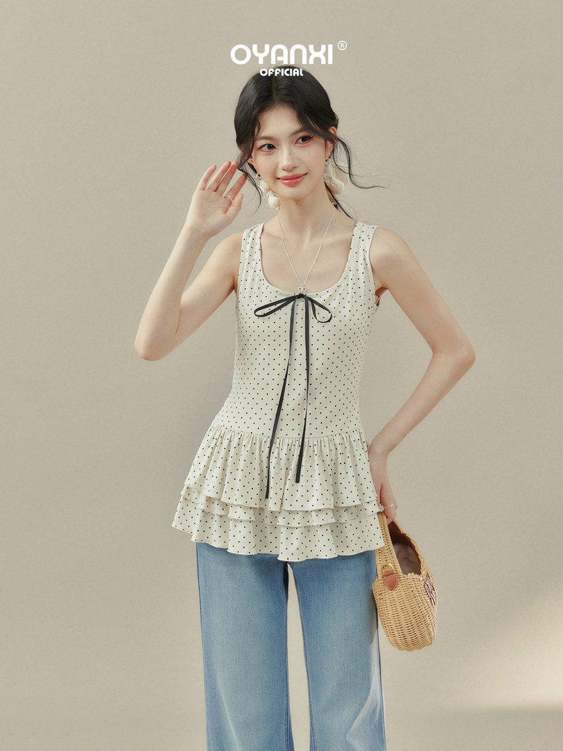 Model wearing a white polka dot sleeveless peplum top with jeans