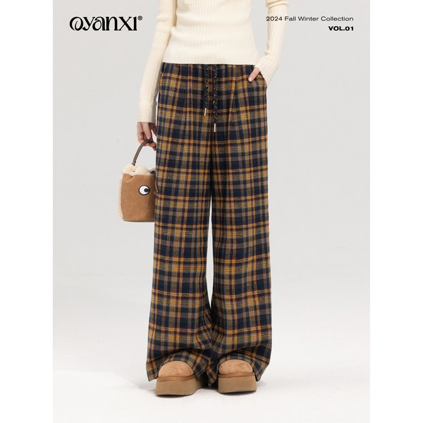Model wearing plaid wide-leg pants with a cream top and winter boots