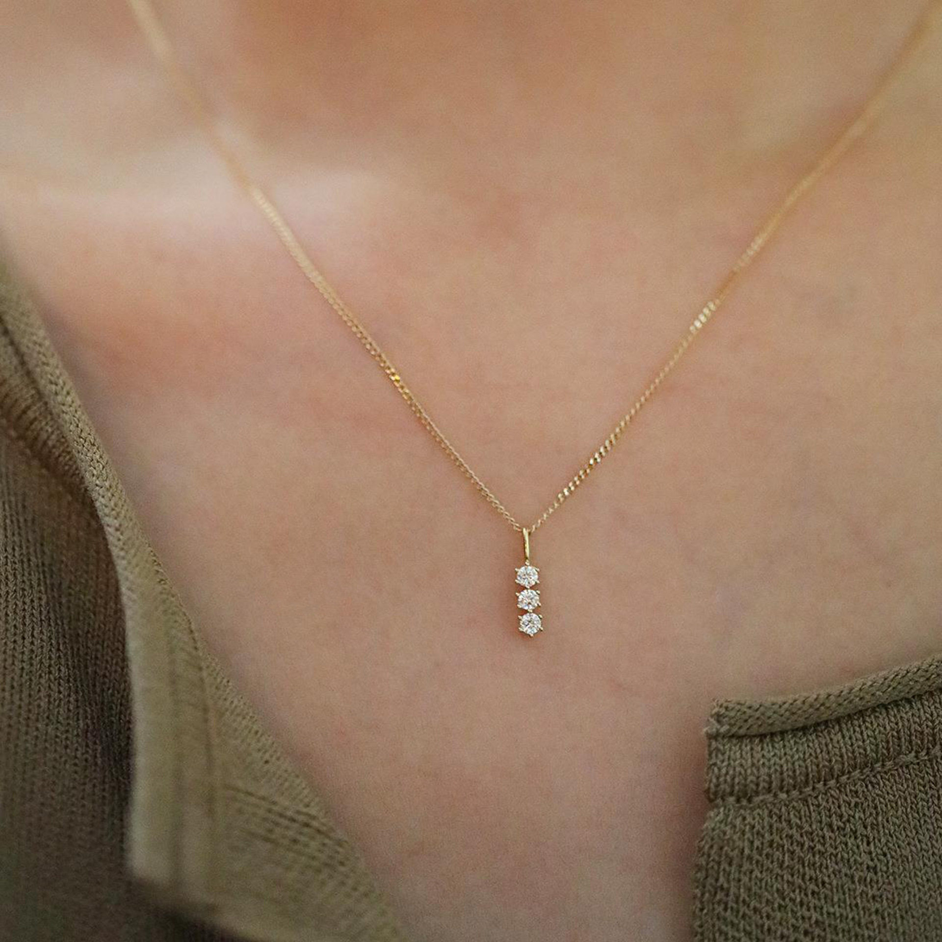9k gold A small pendant with three diamonds in a single vertical bar