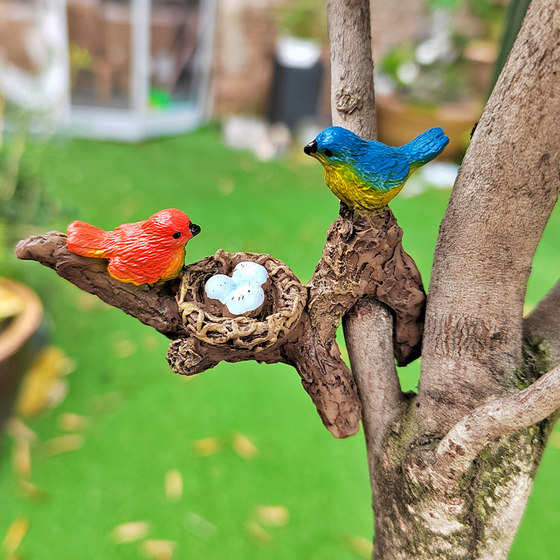 Simulated branch birdbath hanging ornaments on the side of the tank