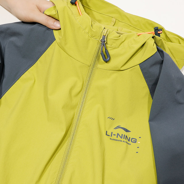 Li Ning ເສື້ອກິລາ windbreaker ສໍາລັບຜູ້ຊາຍພາກຮຽນ spring ແລະ summer ນ້ໍາ repellent ສັ້ນ hooded ເຢັນ windproof ແລະ sunproof ກິລາກາງແຈ້ງສໍາລັບແມ່ຍິງ