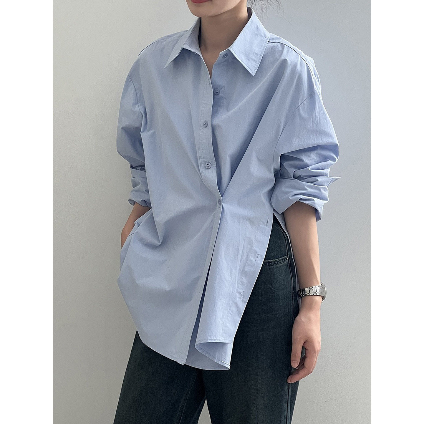 A stylish and chic women's shirt with irregular diagonal buttons, side slits, and a deconstructed design; shorter in the front and longer in the back.