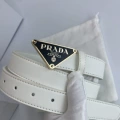 P-shaped gold buckle with black background and white belt