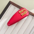 Patent leather-red spring clip [with label on the back]
