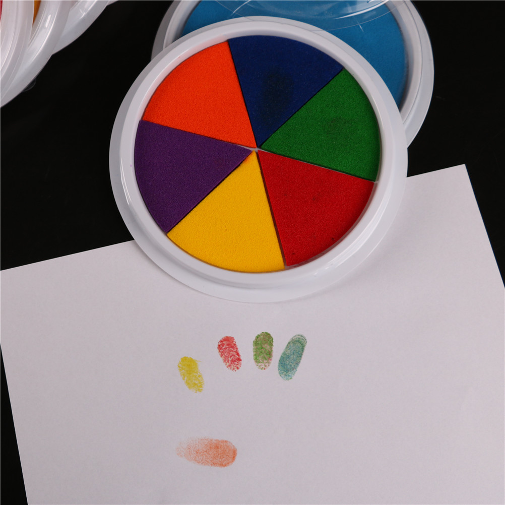 A child's hand finger prints the printed clay pad.