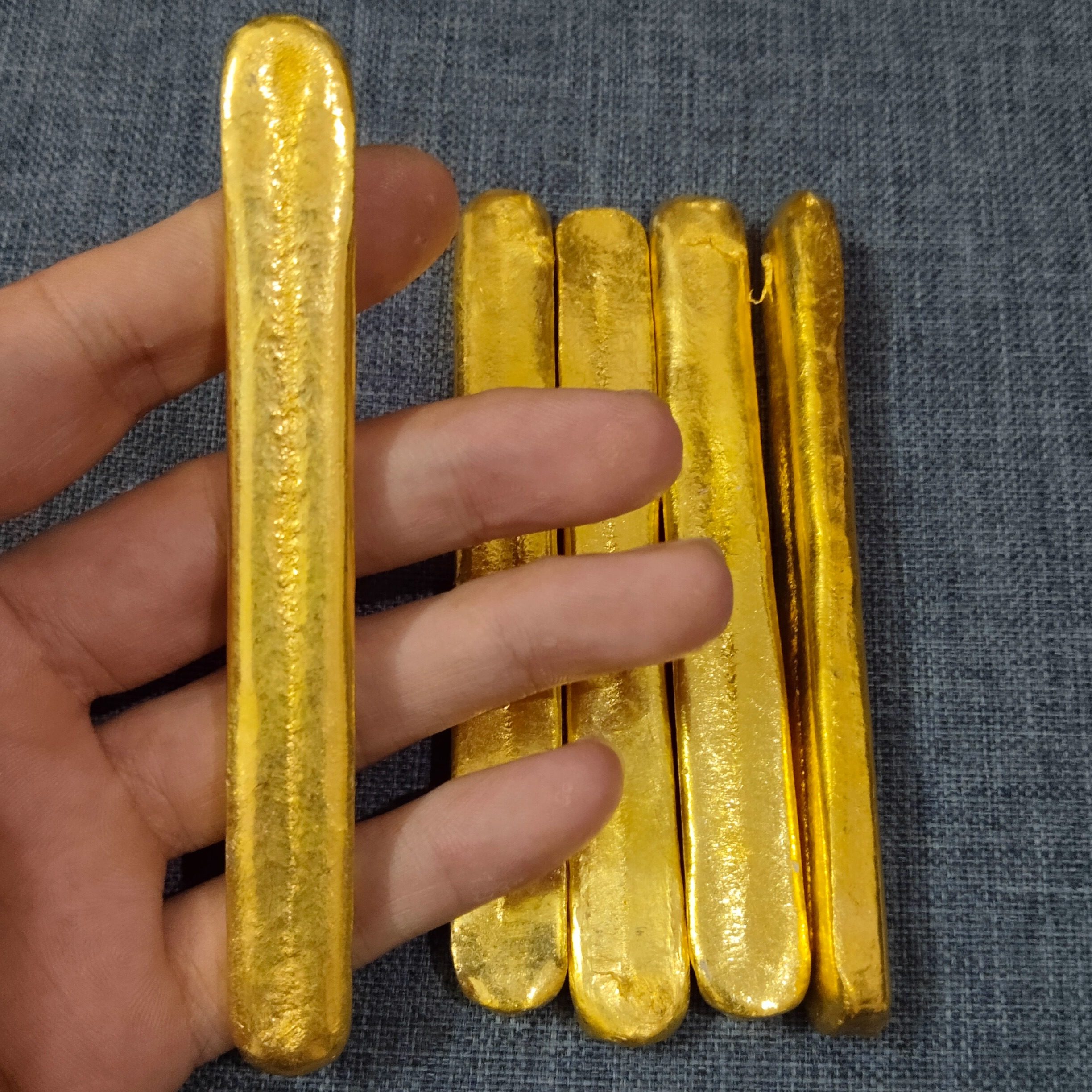 バングラデシュ産の赤い砂金鉱石、金模造品、火で溶かすことはできるが冷却しても変色せず、再成形可能な金塊。